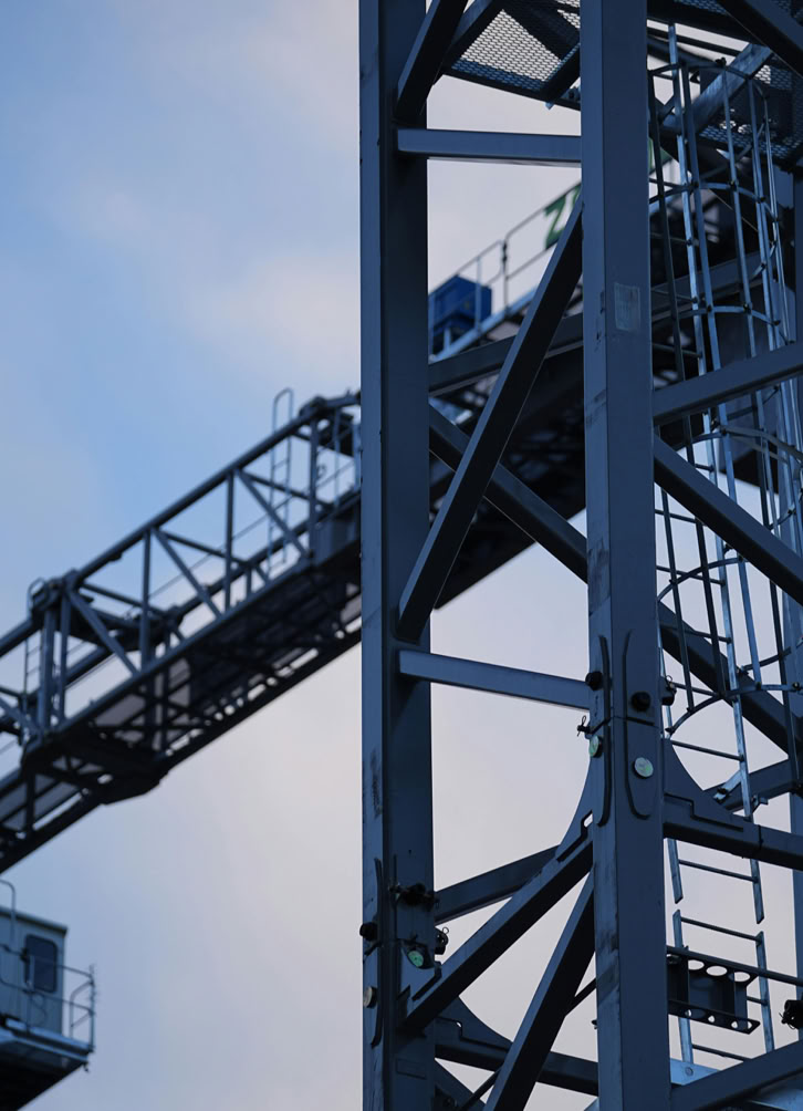 Close-up of a construction crane silhouetted against the sky at dusk.