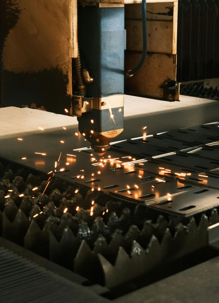 Close-up of a laser cutter in action, producing sparks in a modern manufacturing facility.